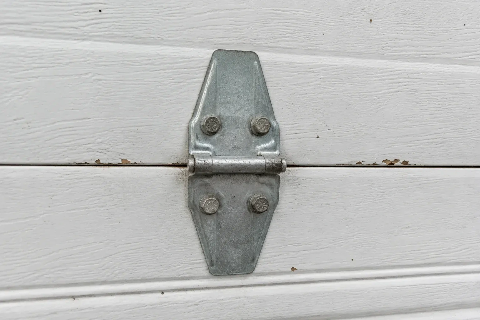 Metal center hinge across a seam in a white sectional garage door. — Garage Door Hinge Replacement, Richmond Hill